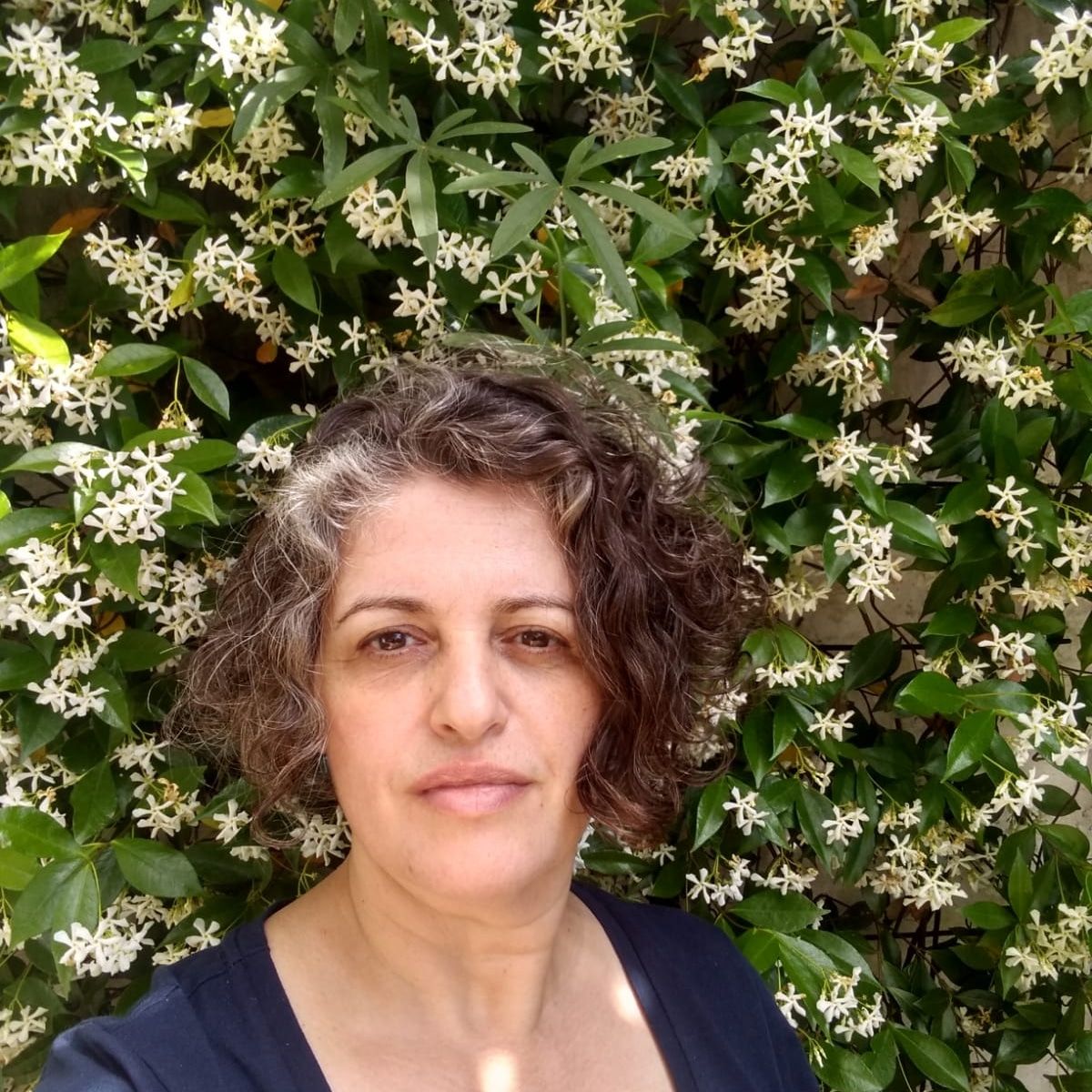 Photograph of Anabela Plos standing in front of flowers